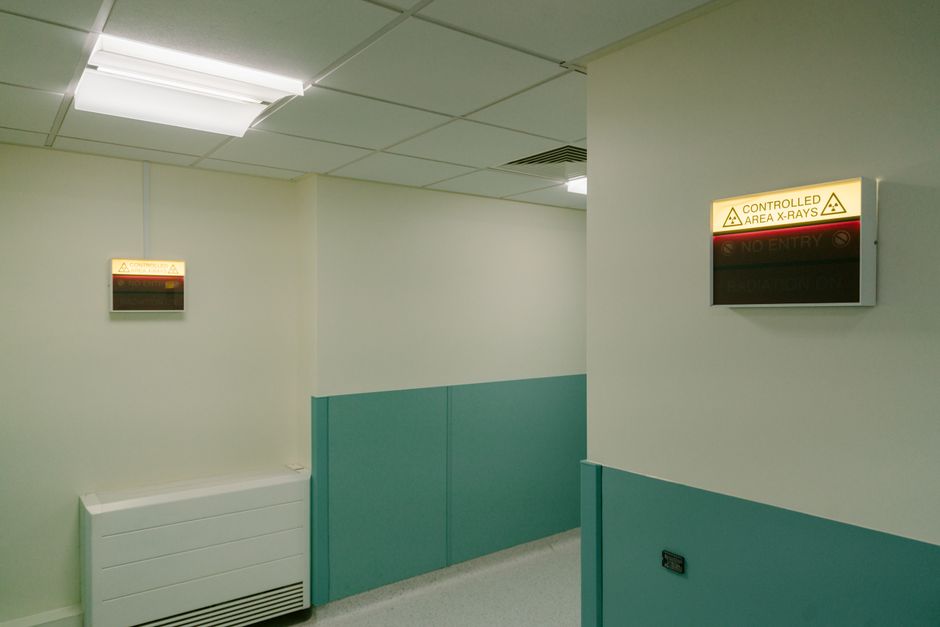 Interior hospital hallway with illuminated X-Ray area warning signs.