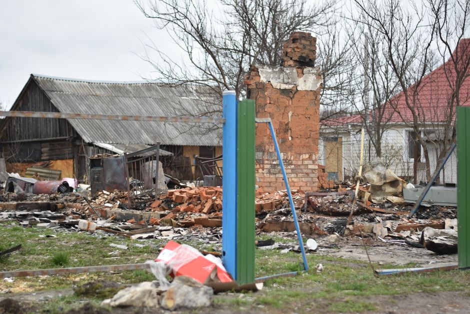 Debris and damage in a rural village affected by a disaster, showing destroyed homes.