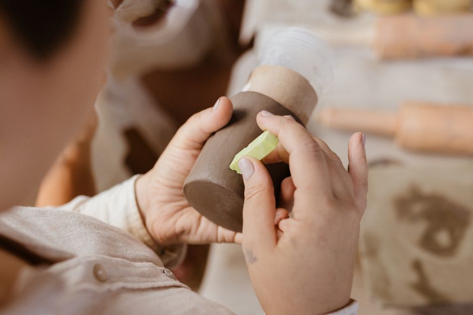 A person skillfully crafting pottery in an indoor setting, showcasing detailed handwork and craftsmanship.