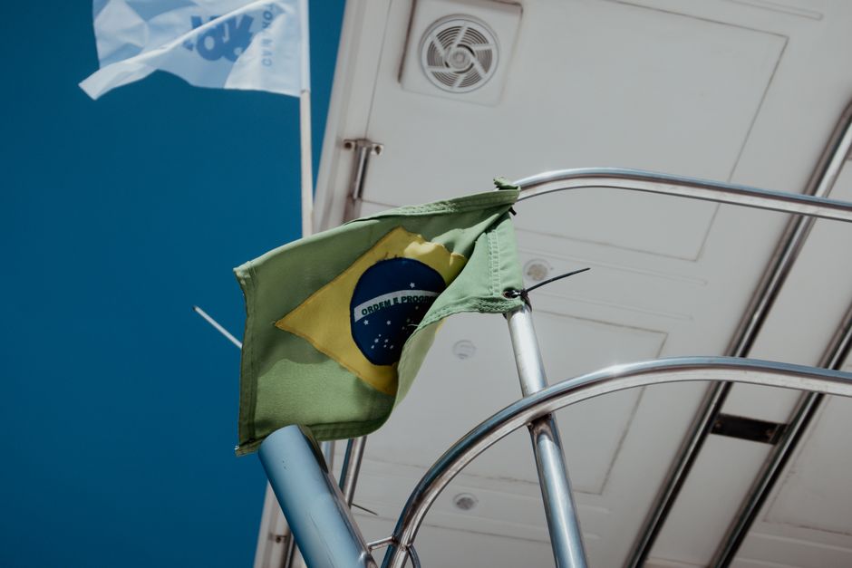 Close-up of the Brazilian flag on a sailboat under clear blue skies.