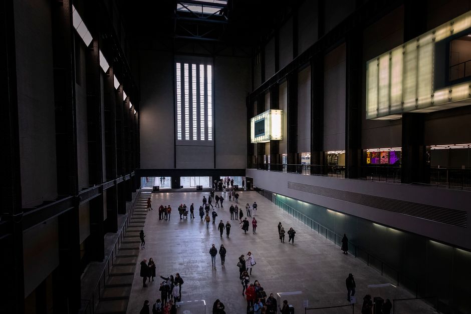 Wide view of visitors in the vast interior of the Tate Modern in London, showcasing industrial architecture.