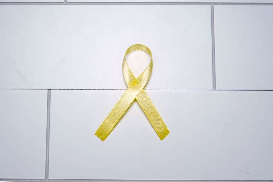Yellow ribbon on white tiles symbolizing awareness and support across various causes.