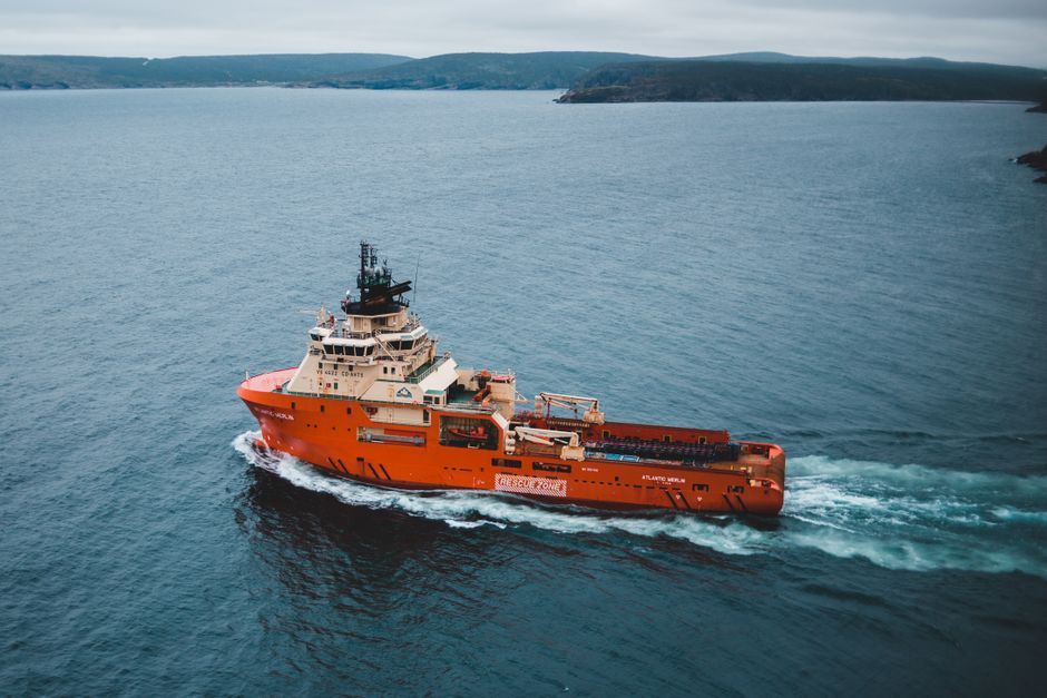 Vibrant orange ship cruising on a calm ocean, showcasing marine transportation.