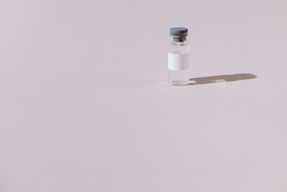 A sterile vaccine vial isolated on a minimalist gray background, emphasizing health and medicine.