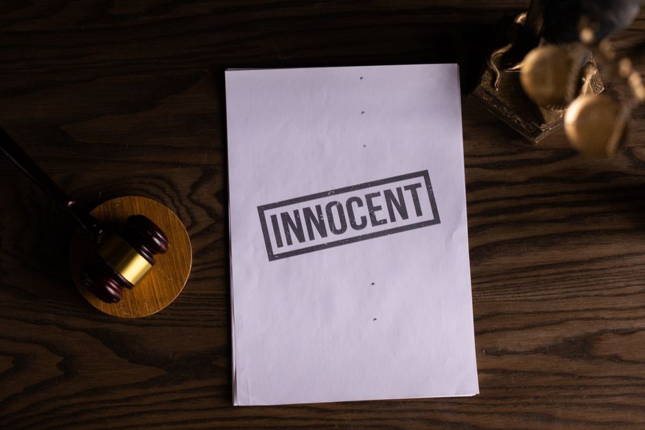 Close-up of legal document stamped 'Innocent' beside a gavel on a wooden desk.