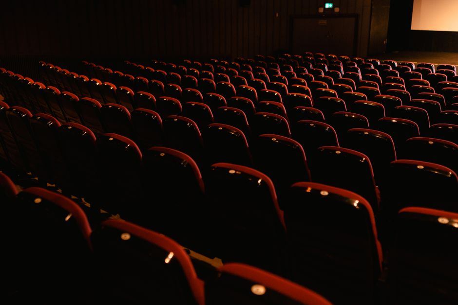 Rows of empty red seats in a darkened movie theater, awaiting audience.