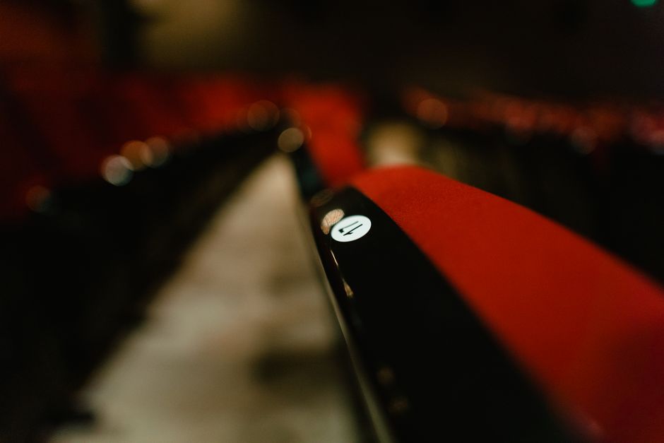 Blurred close-up of red theater seats in an empty auditorium highlighting seat number.