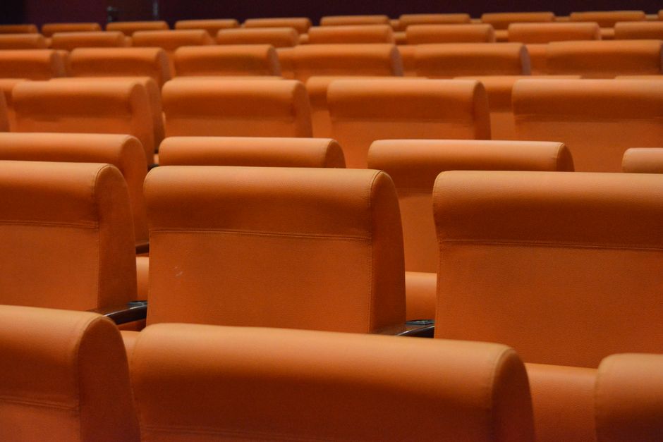 Rows of orange seats in an indoor auditorium, ideal for presentations and events.
